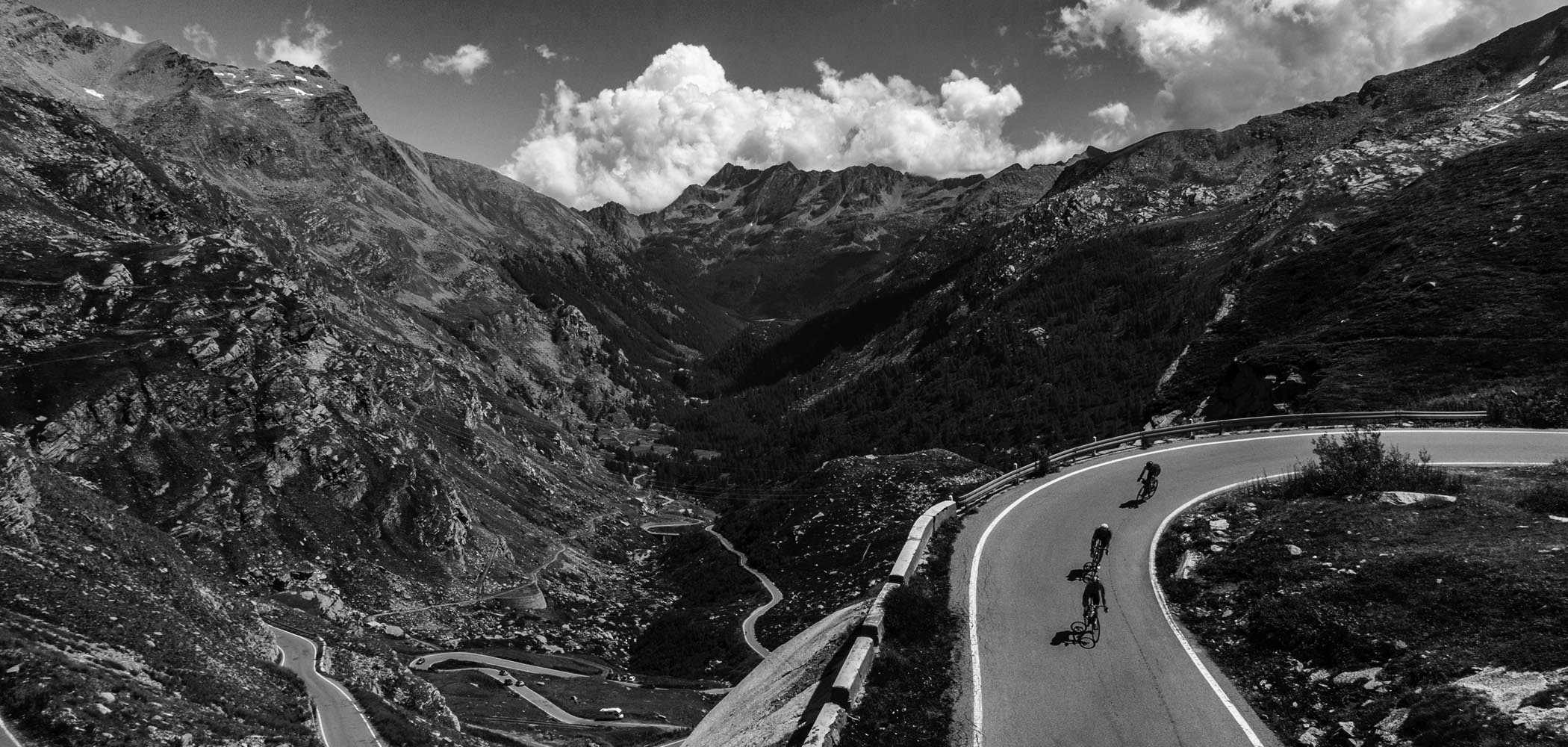 Cyclists descend from Nivolet Pass in Italy wearing black Luxa Supreme cycling jerseys.